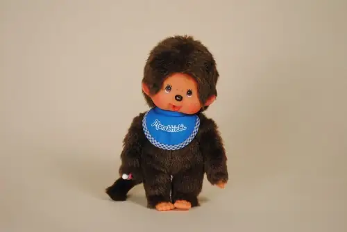Peluche Kiki Monchhichi de 19 cm avec son bavoir bleu de la marque Sekiguchi